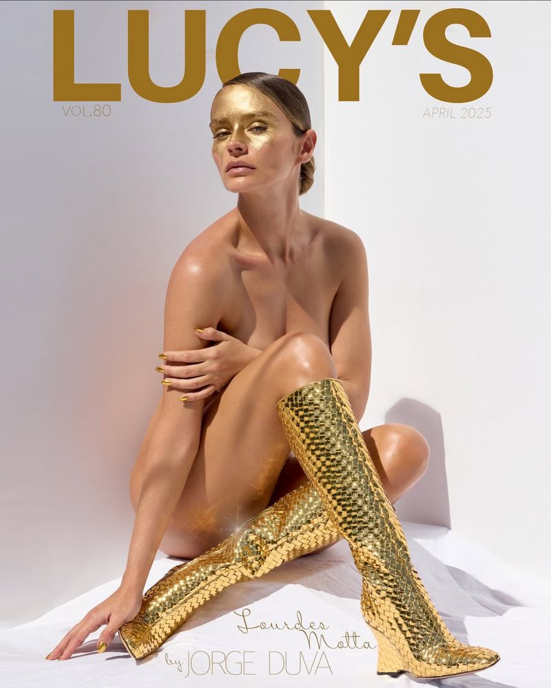 Magazine cover featuring a person with gold face paint and knee-high gold boots, contrasted against a bright white background.