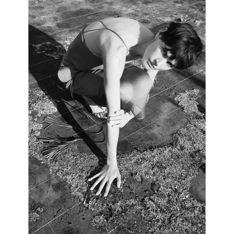 Model Saskia de Brauw crouching outdoors on paved ground in a look from the Gabriele Colangelo S/S 25 collection.