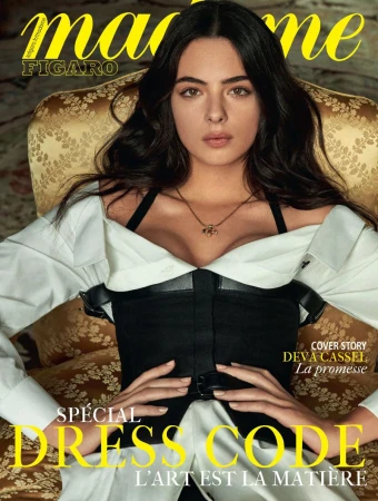 Magazine cover featuring a woman with dark hair wearing a white shirt and black corset, posed in a chair with ornate gold fabric.