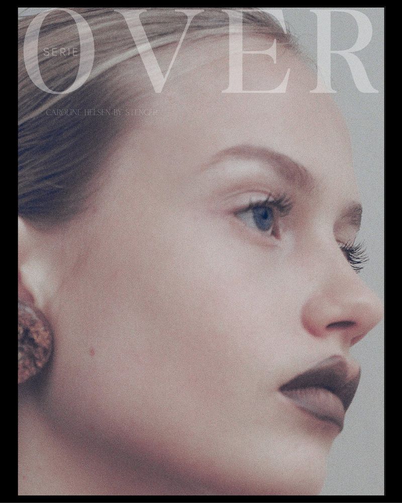 Close-up beauty portrait of model Caroline Helsen wearing dark matte lipstick and a circular earring against a neutral grey backdrop.