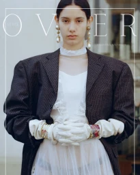 Model wearing structured dark oversized blazer and white gloves with layered pearl earrings for editorial project Over Series