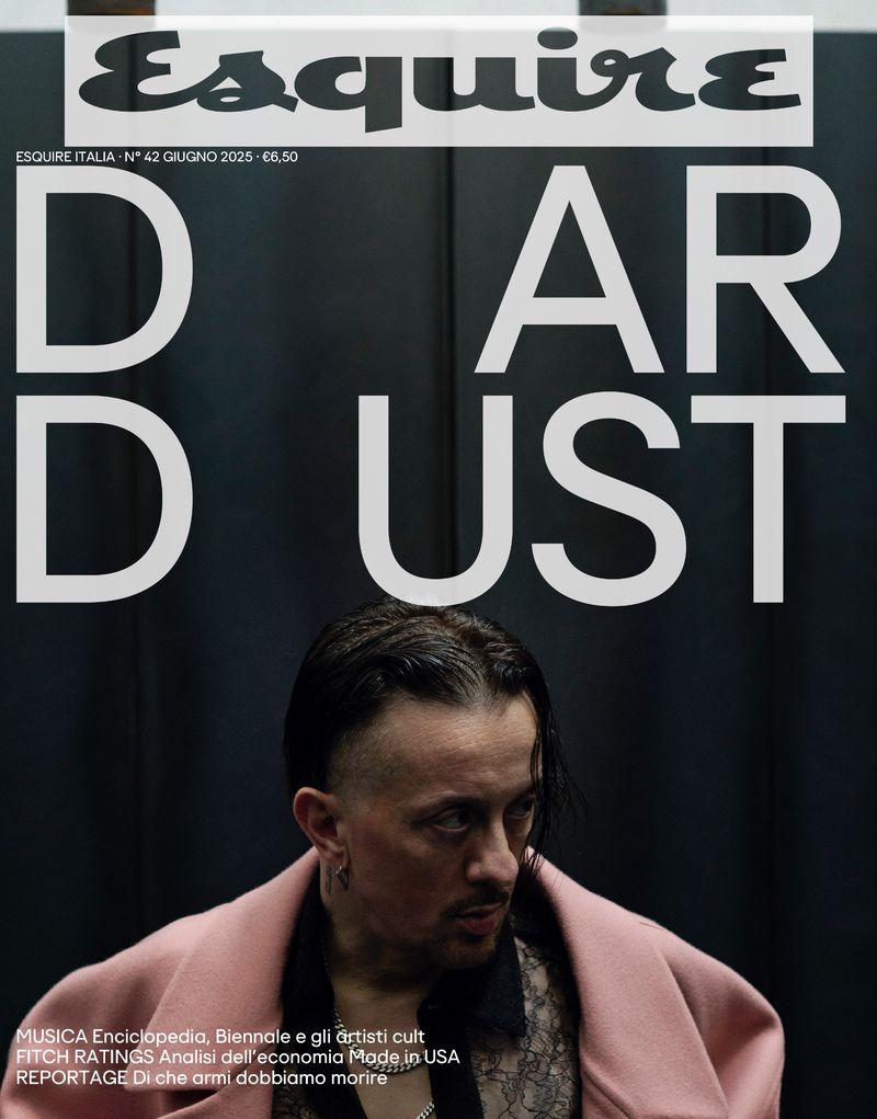 Esquire Italia magazine cover featuring a portrait of a man with dark hair and a pink coat against a dark gray background with text overlay.