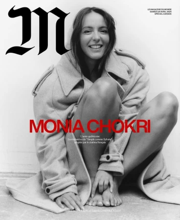 Magazine cover of Monia Chokri sitting barefoot in an oversized light trench coat against a white background.