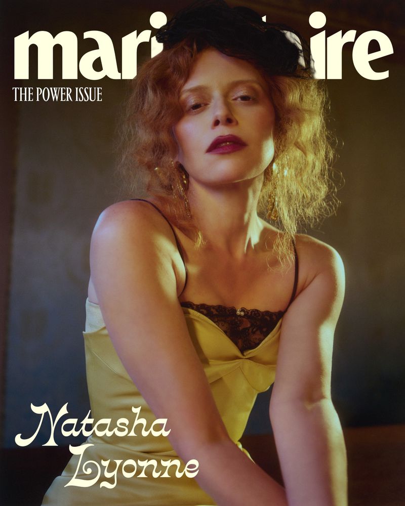 Magazine cover featuring Natasha Lyonne in a yellow dress and black hat, posing indoors with dim lighting and soft focus.