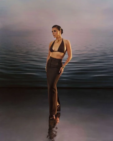 Eva Longoria wearing a dark halter top and skirt against a calm water backdrop for BYRDIE Summer Issue 2025 Cover