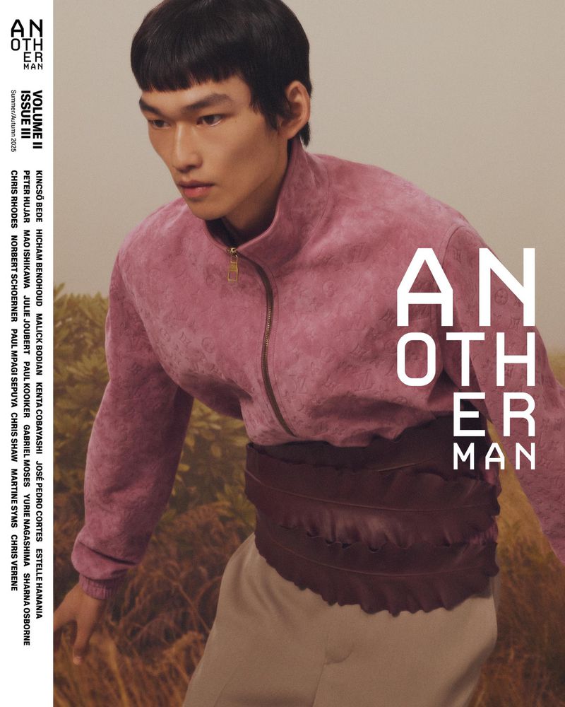 Magazine cover featuring an Asian male model wearing a pink jacket and brown belt, standing in a field with wheat-colored grass.