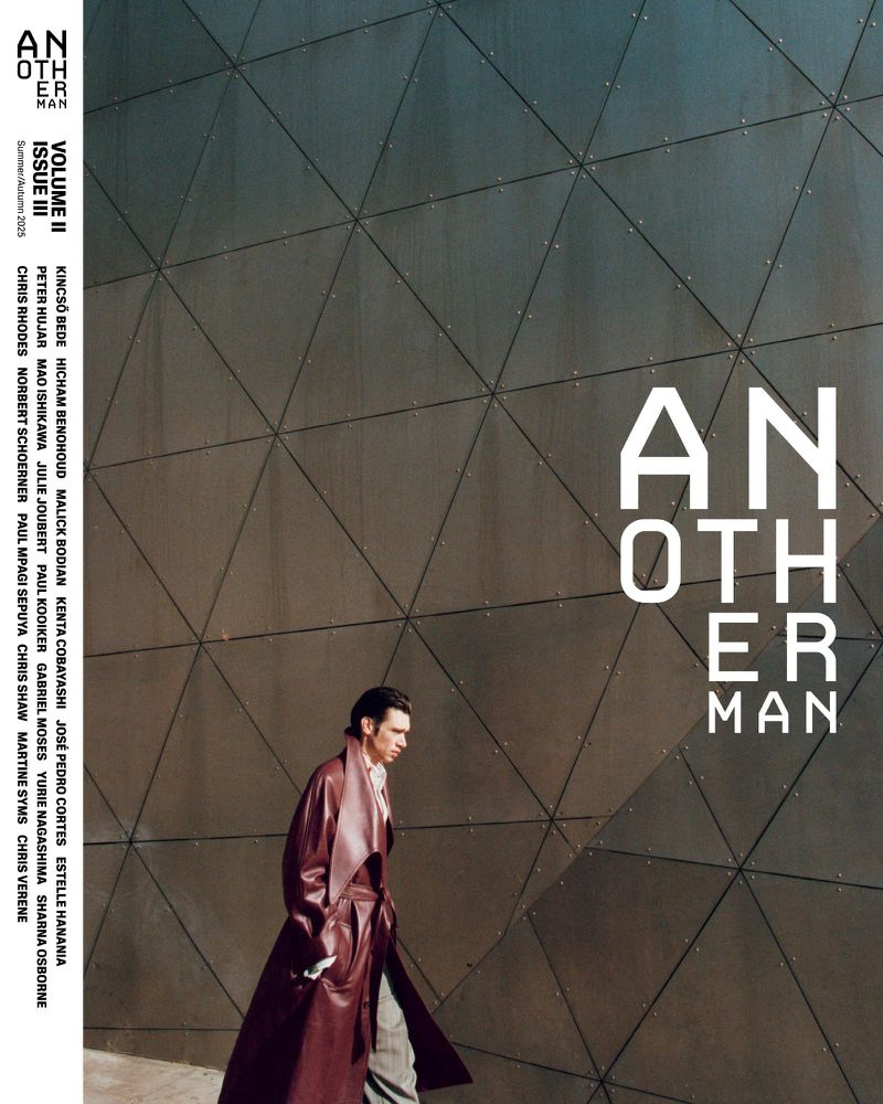 Magazine cover featuring a man in a coat walking against a geometric wall, with prominent magazine title and cover text.