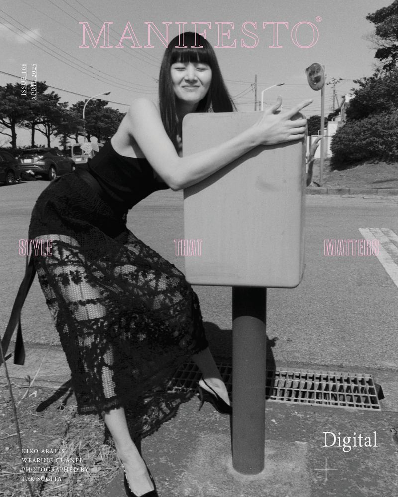 Monochrome fashion shot of a smiling Asian woman in a black dress, leaning on a traffic signal box by a street, magazine cover.