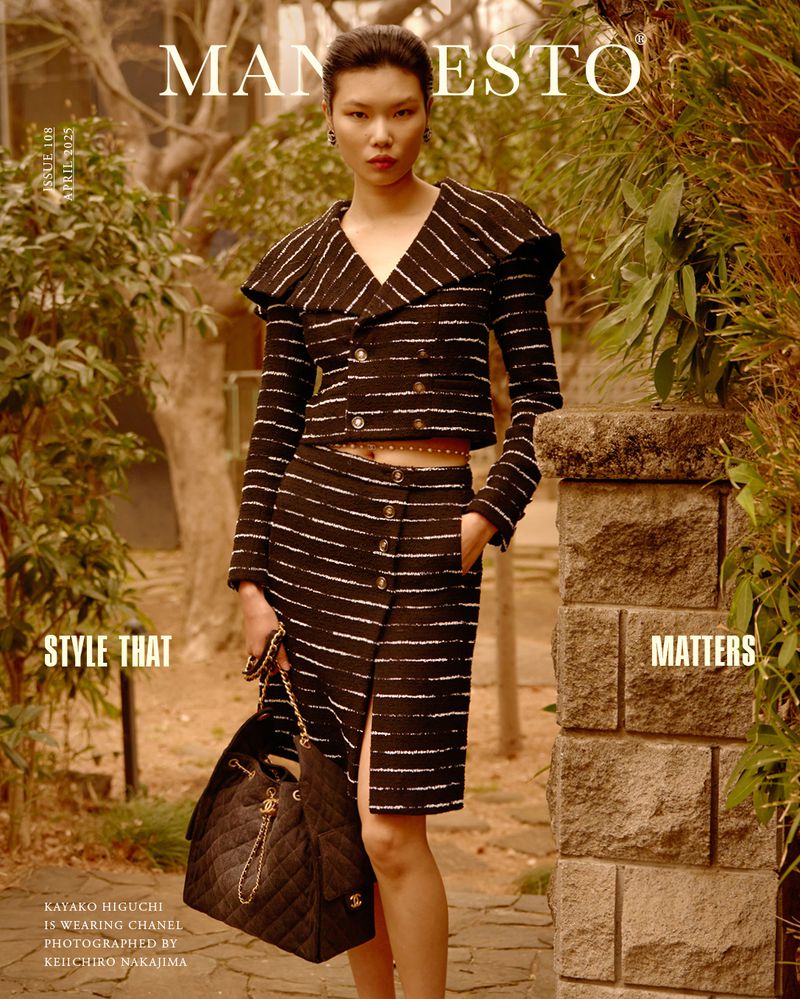 Asian woman poses in Chanel striped skirt and jacket, holding a bucket bag outdoors, featured in Manifesto magazine fashion editorial.