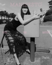 Black and white editorial cover image featuring a model in a black lace dress hugging a street sign post outdoors