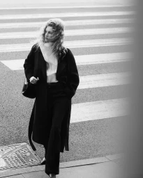 Model Apolline Rocco Fohrer walking outdoors in a black coat for COS Outerwear 2024