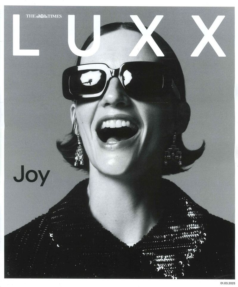 Black and white image of a woman with sunglasses, laughing, wearing a sequin jacket, and dangling earrings. The word 'Joy' is on the image.