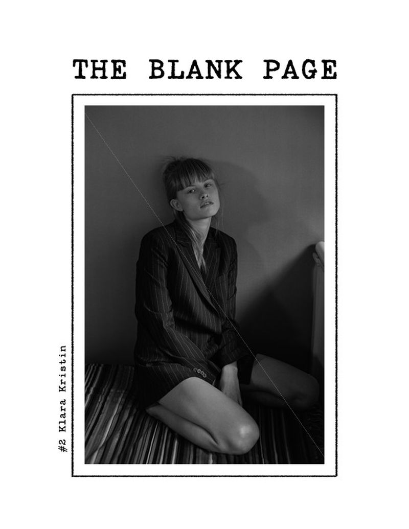 Black and white magazine cover photograph featuring a woman in a pinstripe jacket sitting on a striped surface in an indoor setting.