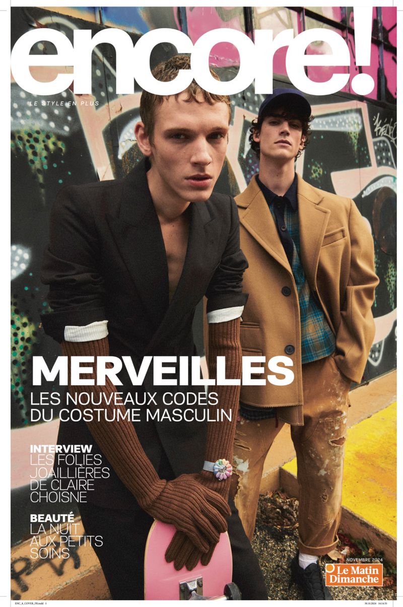 Magazine cover featuring two adult male fashion models wearing stylish outerwear in front of graffiti-covered wall backdrop.