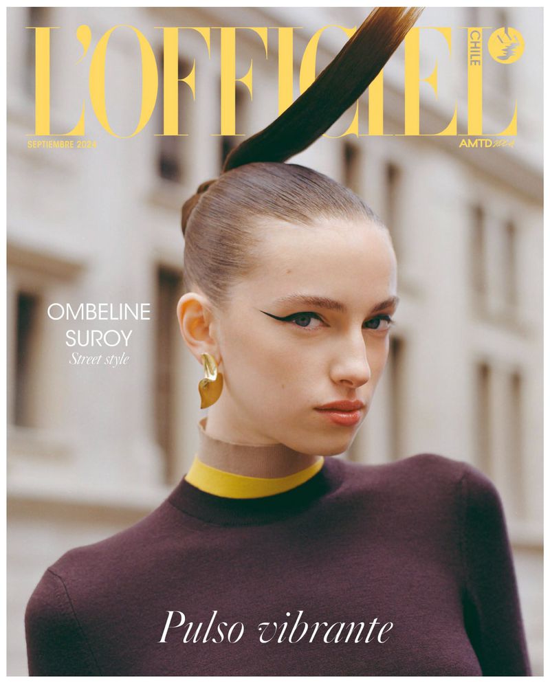 Fashion magazine cover featuring a woman with dramatic eyeliner, gold earrings, and a high ponytail against an urban backdrop.
