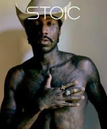 Shirtless tattooed man wearing a cowboy hat and rings, captured in an editorial portrait for Stoic magazine.