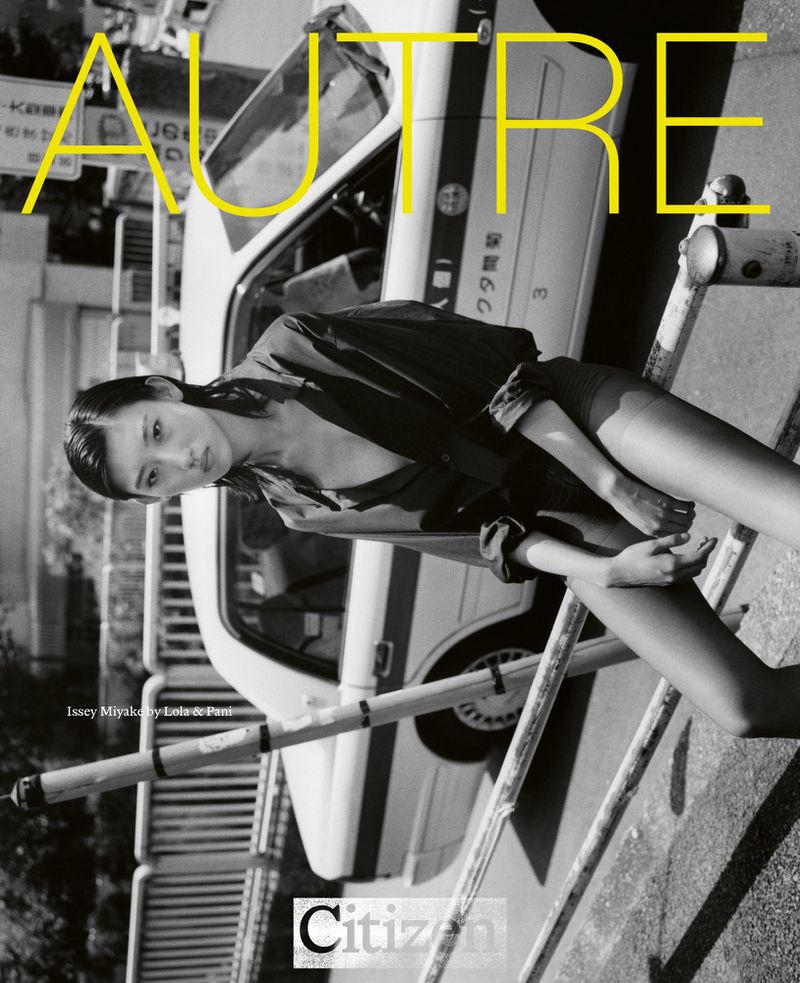 Black and white fashion editorial shot of a young Asian woman lying on a pedestrian barrier in front of a taxi, fashion and style.
