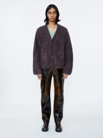 Model wearing a dark fuzzy knit cardigan and glossy brown trousers against a plain white background