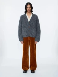 Model wearing a grey fuzzy cardigan and brown corduroy trousers against a plain white studio background.