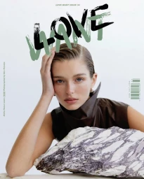 Model Stella Hanan rests her head on her hand behind a veined marble slab on the cover of Love Want Issue 34 against a white backdrop.