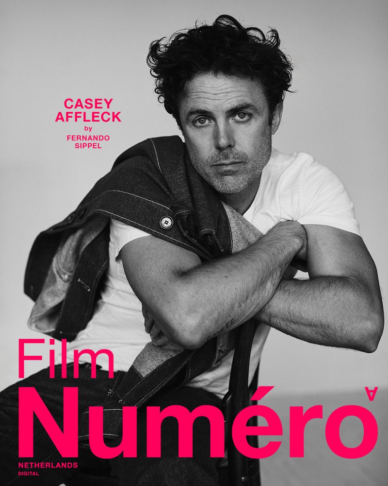 Black and white portrait of Casey Affleck wearing a white t-shirt and denim jacket, with 'Numero' magazine text overlay.