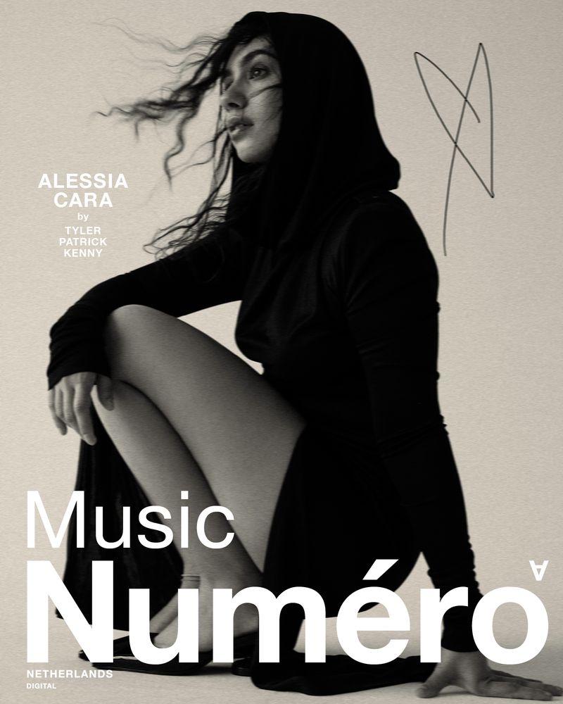 Alessia Cara gazes off-camera in a black hooded dress for Numéro Netherlands Music Digital, captured in a monochrome portrait.