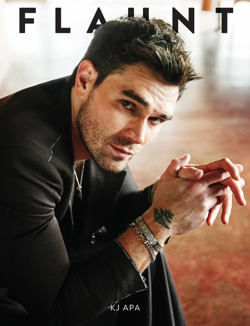 Portrait of actor KJ Apa for Flaunt Magazine. He is wearing a black blazer and silver bracelets. The backdrop is a neutral tone.