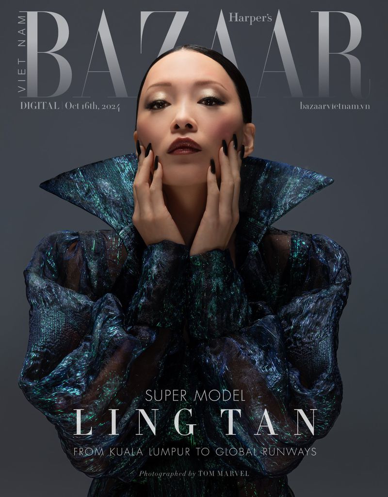 Fashion magazine cover featuring an Asian woman with hands framing her face, wearing a reflective textured dress with a wide collar.