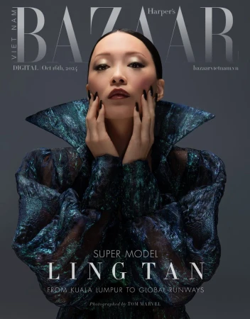 Fashion magazine cover featuring an Asian woman with hands framing her face, wearing a reflective textured dress with a wide collar.