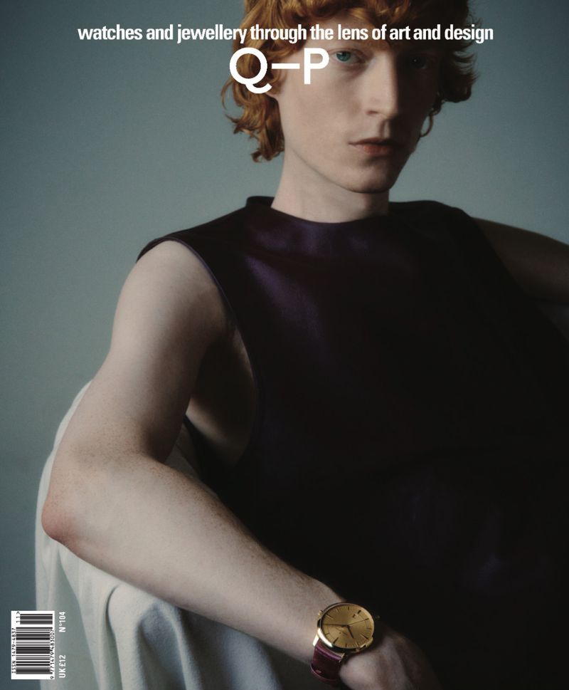 Fashion magazine cover featuring a red-haired male model wearing a sleeveless top and gold wristwatch indoors against a plain background.