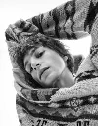 Model wearing a patterned knit sweater with arms raised behind head, shot in black and white for DLMAU editorial by Steven Chee.