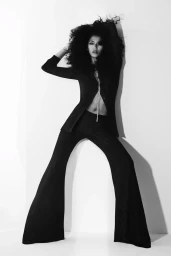 Model in black flared trousers and jacket posing against a white background for Tom Ford S/S 25