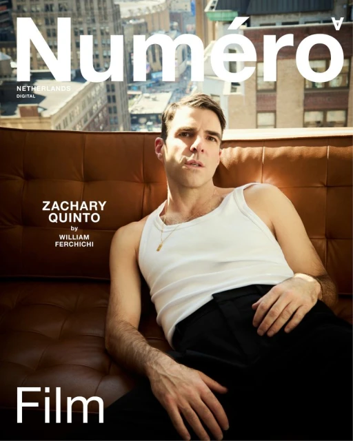Magazine cover featuring Zachary Quinto reclining on a brown couch with a city view in the background, wearing a white tank top.