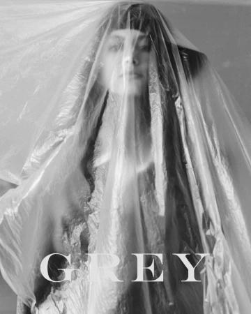 Black and white editorial portrait of model Vanessa Pompucci looking through a crinkled translucent plastic sheet with GREY masthead.