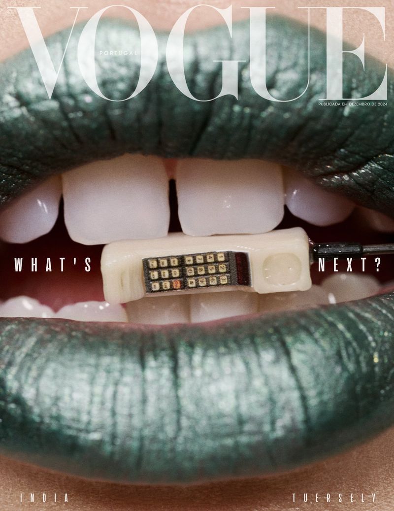 Close-up of a Vogue magazine cover featuring a person's mouth with green lipstick and a small computer device held between the teeth.