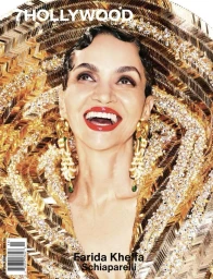 Close-up portrait of Farida Khelfa smiling wearing large gold earrings and an ornate textured gold headpiece for 7 Hollywood Magazine.