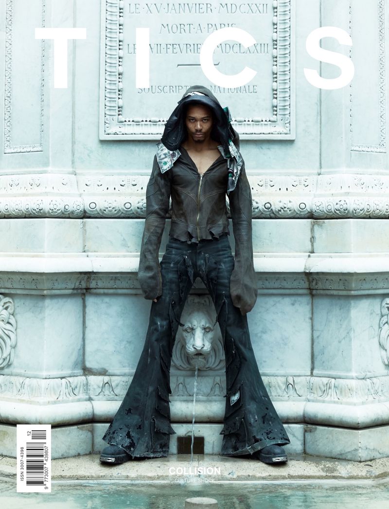 Fashion magazine cover featuring a male model wearing a dark hooded leather jacket and bell-bottom jeans, standing in front of a fountain.