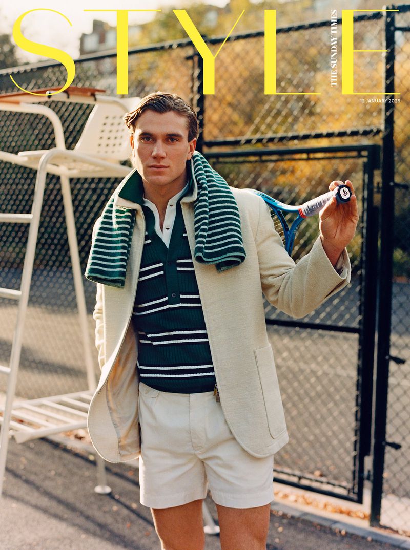 Magazine cover featuring a man in a blazer and shorts holding a tennis racket on a tennis court against a tree background.