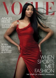 Angel Reese wearing a red evening dress with a high slit against a textured concrete wall for American Vogue Winter 2025