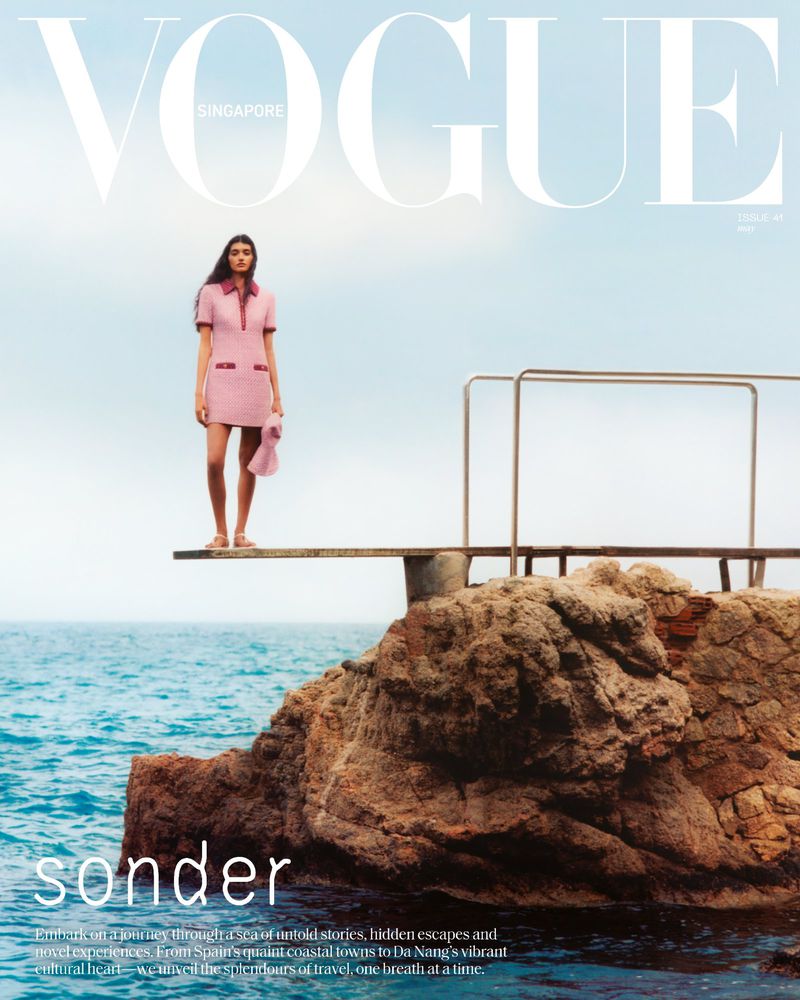 Vogue Singapore cover featuring a woman in a pink dress on a diving board by the sea, with blue skies and the magazine's logo.