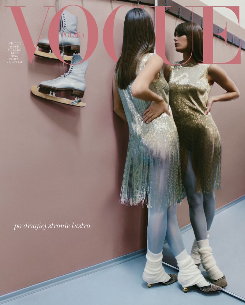 Two models in sequined dresses pose on a magazine cover with vintage ice skates and light blue tights indoors with a pink wall.