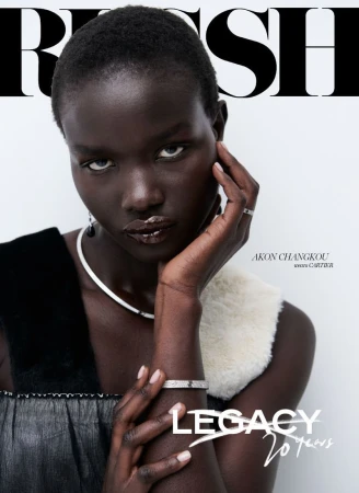 Magazine cover featuring a dark-skinned woman with a serious expression, wearing a white collar, and posing with her hand to her face.
