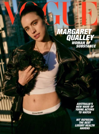 Vogue cover featuring Margaret Qualley in a black leather jacket, white top, and dark pants, holding a small dog, with city buildings in the background.