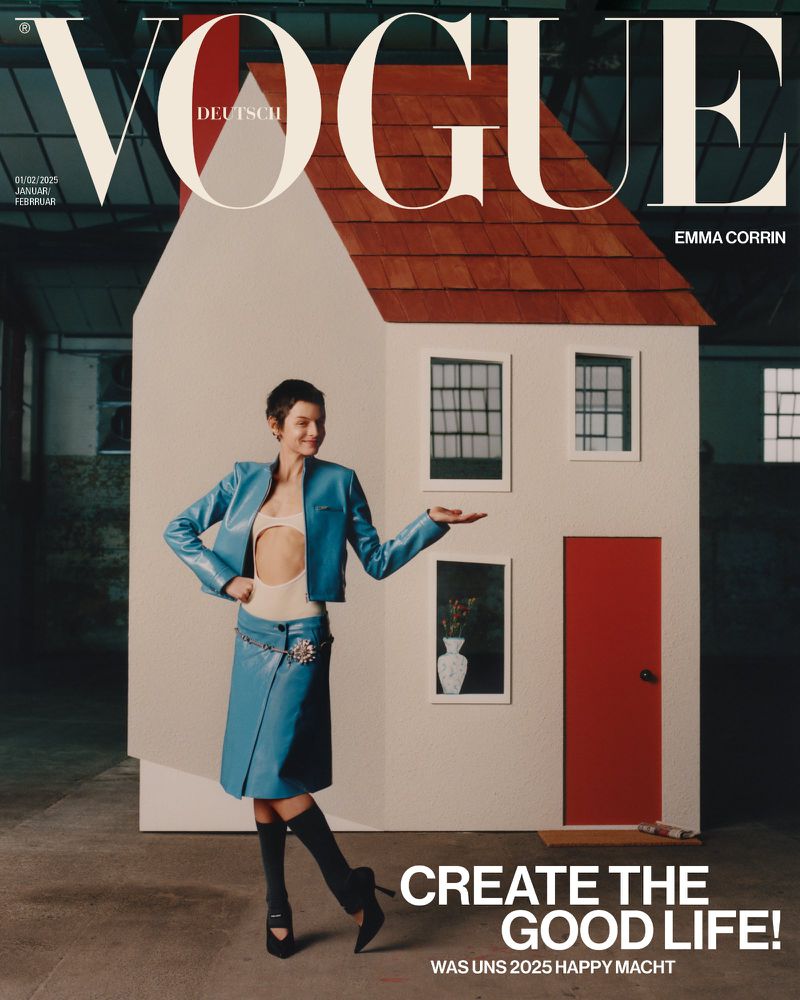 Vogue Deutsch cover featuring Emma Corrin in a blue outfit posing in front of a white house prop in a studio setting.