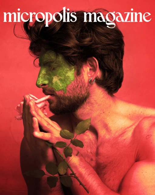 Magazine cover featuring an adult male with a green face mask, holding a rose in front of a red background with magazine text.