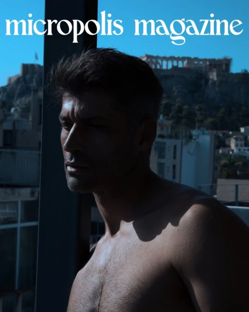 Magazine cover featuring a shirtless man against a cityscape backdrop, including the Acropolis, under natural lighting.