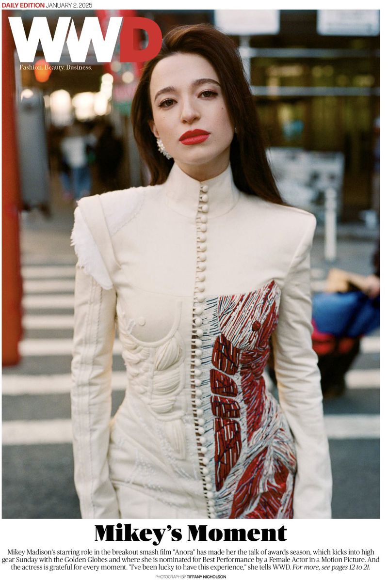 WWD fashion cover featuring a stylish woman with dark hair, wearing a unique cream and red dress, set against a blurred street background.