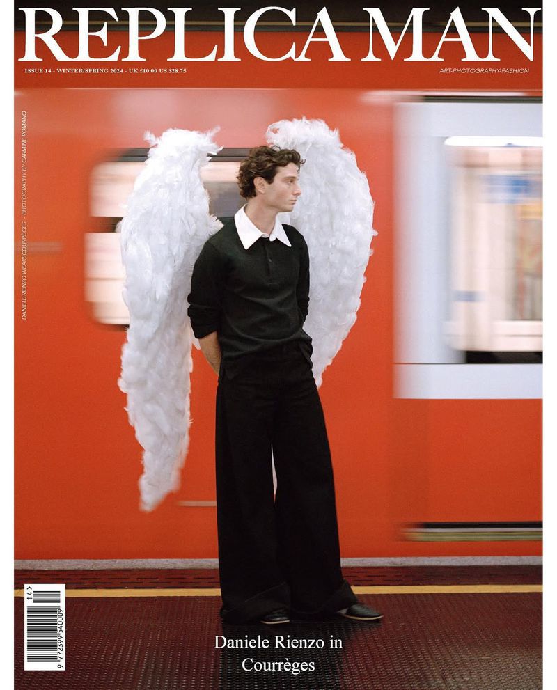 Magazine cover featuring a slender man with wings standing in a train station wearing a black outfit against a red train backdrop.