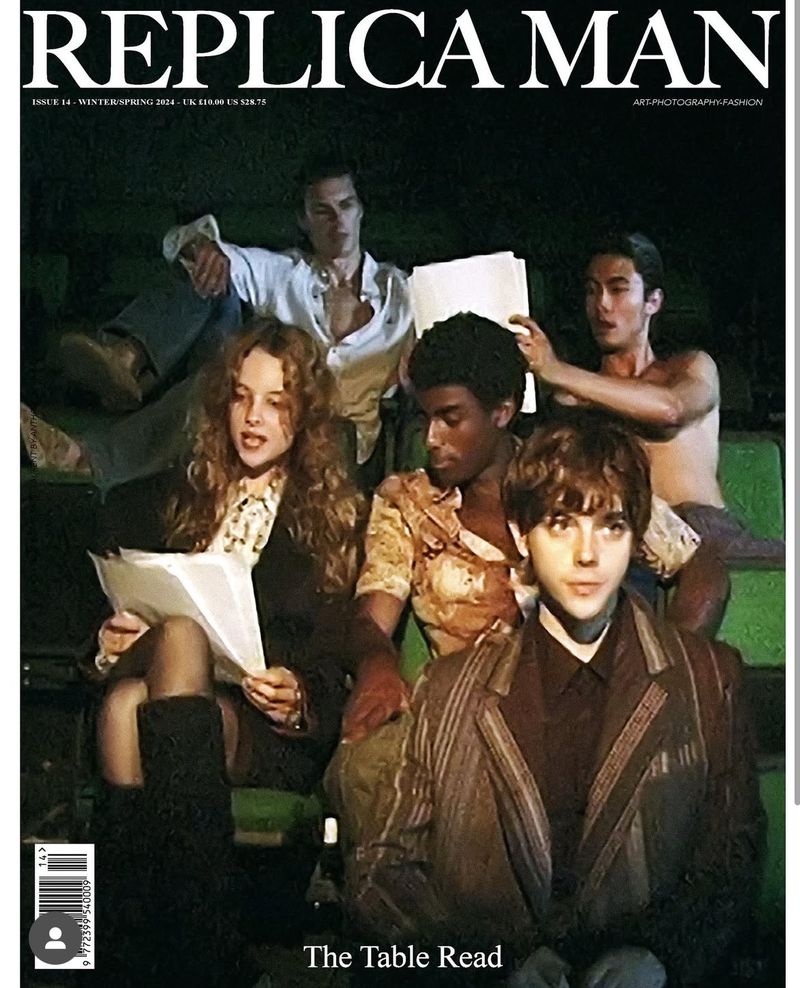 Fashion magazine cover featuring a group of men and a woman in an indoor theater setting, holding papers as if participating in a table read.