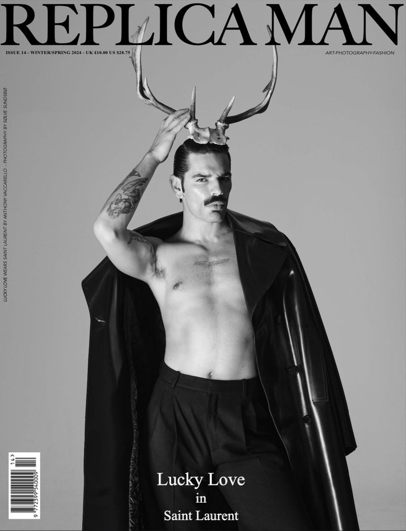 Replica Man magazine cover featuring a man with a mustache, an open black coat, and deer antlers on a light gray background.